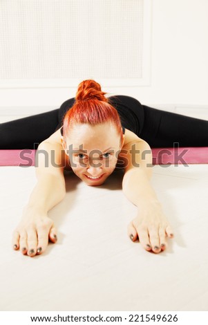 Redhead woman exercising yoga laying down on floor legs stretched closeup