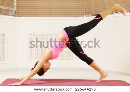 Young brunette exercising yoga pose one leg up