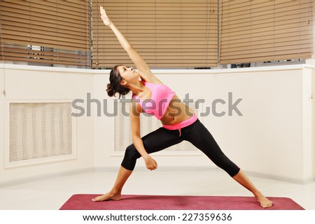 Young brunette arm and leg in straight line yoga pose looking at palm