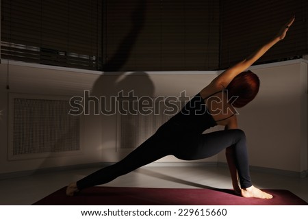 One line yoga pose in dark gym rear view