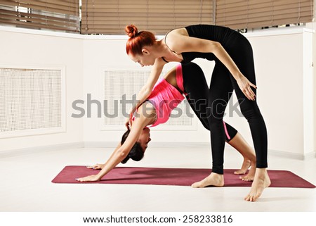 Instructor corrects head bending in downward face dog yoga pose