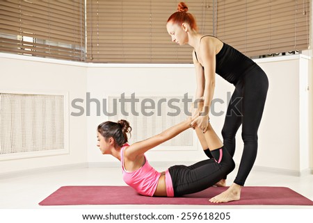 Yoga instructor helping brunette in back bend pose