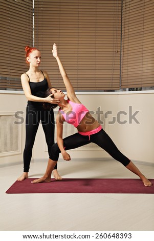 Yoga instructor helping brunette to keep head in line