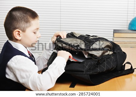 Schoolboy taking books out of bag in classroom