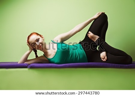 Relaxed yoga woman laying down at the green wall legs crossed