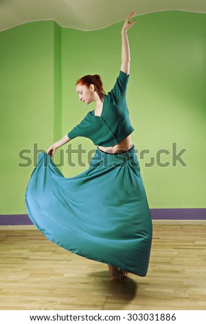 Caucasian redhead woman dancing in a green room