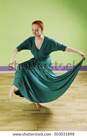 Caucasian redhead woman dancing in a green room