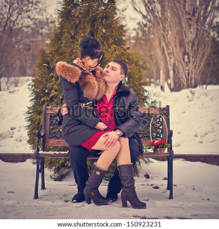 love couple sitting on a bench in winter park