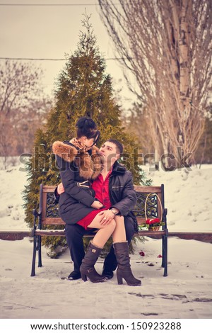 love couple sitting on a bench in winter park