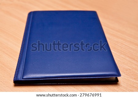 blue book for storing coins in a leather-bound on a wooden background, selective focus