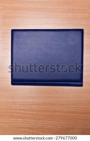 blue book for storing coins in a leather-bound on a wooden background, selective focus
