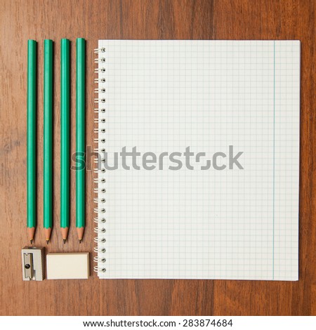 pencil sharpener and an eraser near an open notebook on a wooden background