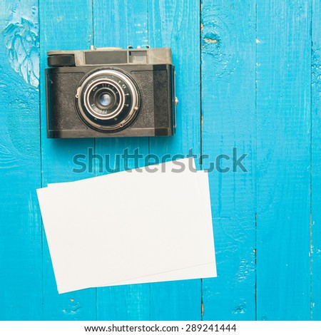 retro camera and photos over blue wooden background