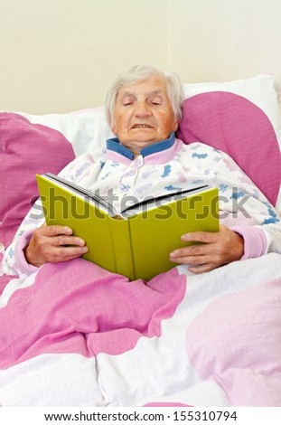 Happy grey haired senior woman reading a book