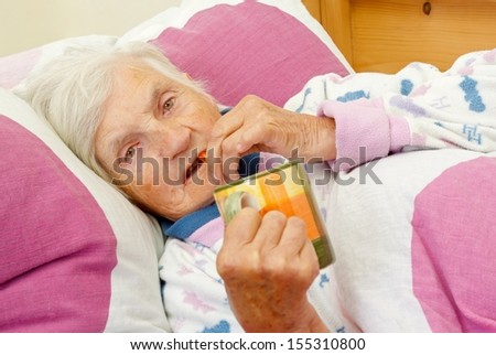 Elderly woman holding a cup of tea and her medicine