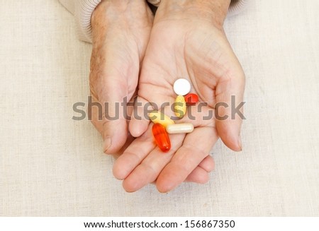 Elderly woman holding pills in her hand