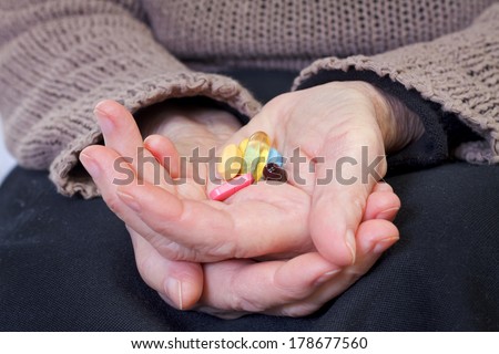 Close up of an elderly hand holding pills