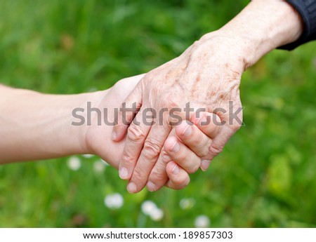 Doctor\'s hand holding a wrinkled elderly hand