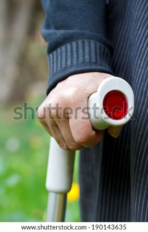 Close up of an elderly hand holding a crutch