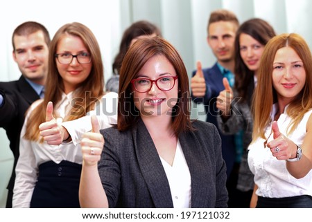A business team standing in office after a successful business with thump up