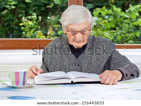Happy elderly woman reading a book in the room