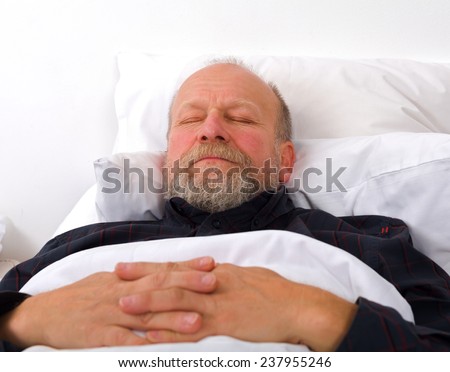 portrait of an elderly man holding his hands in the bed