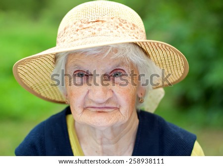 Joyful elderly woman with a hat sitting in the garden