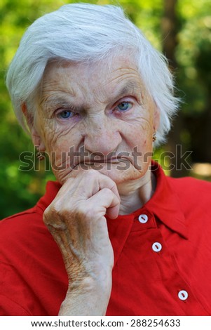 Distressed wrinkled elderly woman relaxing in the garden