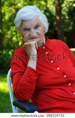 Distressed wrinkled elderly woman relaxing in the garden
