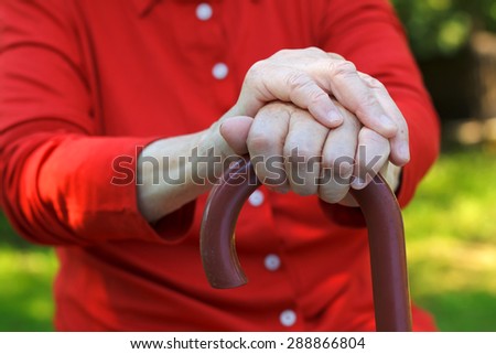 Close up of an elderly hand holding a cane
