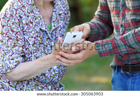 Grandmother and grandson using a white smartphone