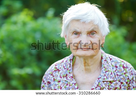Beautiful wrinkled elderly woman relaxing in the garden