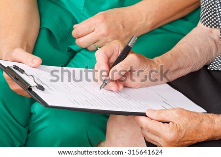 A senior woman\'s hand signing a document