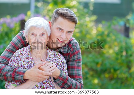 Grandson hugging her beautiful  senior wrinkled grandmother