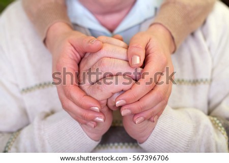 Close up picture of elderly hands with young caretaker\'s hands
