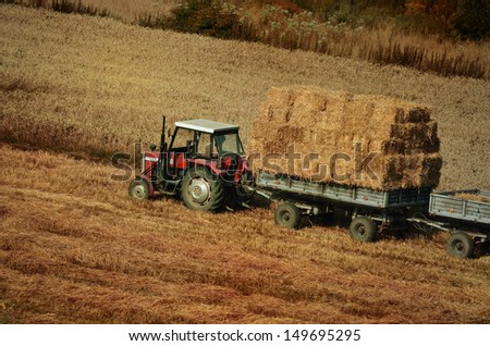 Tractor collecting pack straw in the field