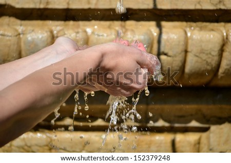 Young woman washing hand under the stream of water