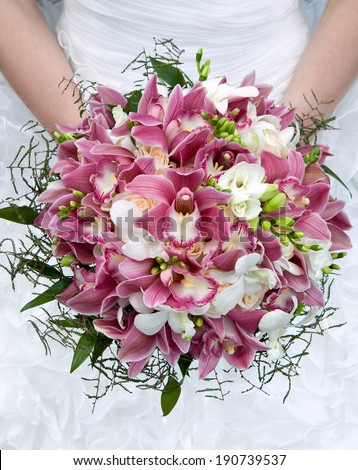 Bouquet of orchids, roses and other flowers in the bride\'s hands closeup. Bouquet of fresh flowers for the wedding ceremony.