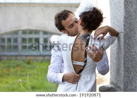 Woman with a tattoo kisses the man on background of old building. Man undresses woman\'s dress.