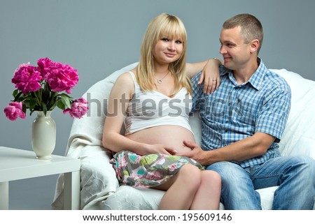 Pregnancy. Couple expecting a baby sitting on the couch enjoying the moment.
