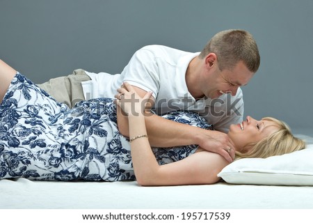 Pregnancy. Smiling couple awaiting a baby.. Happy husband embracing his pregnant wife in bed at home.