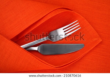 Orange linen napkin and tablecloth with knife and fork. Table setting for Halloween day.