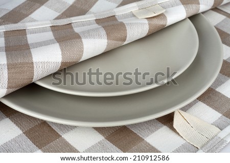 Towel in beige plaid and gray plates. Kitchen linen towel and plates.