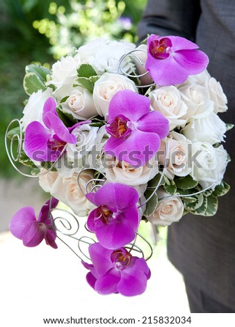 Bouquet of fresh flowers for the wedding ceremony. Bouquet of orchids, roses and other flowers in the groom\'s hands closeup.