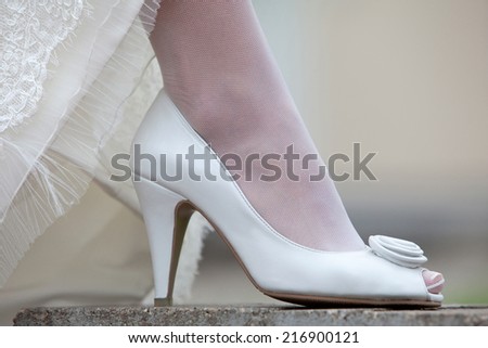 Women\'s shoes and hem of wedding dress. Leg of the bride in a white shoe.
