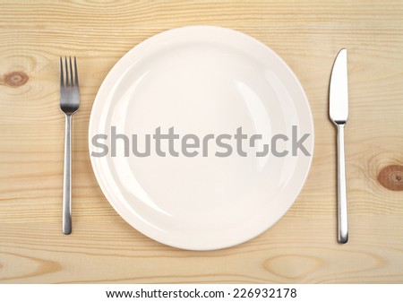 empty plate with fork and knife on the wooden table