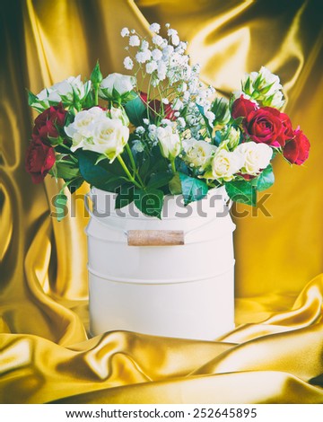 roses in a bucket on a background of gold satin