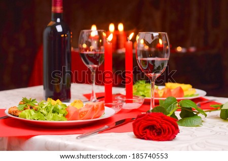 Romantic dinner with wine, candles and a red rose on a table