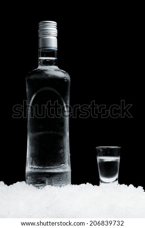 Studio shot of bottle with glass of vodka standing on ice on black background