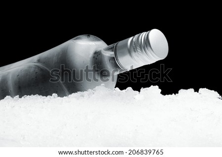 Close-up view of bottle of vodka lying on ice on black